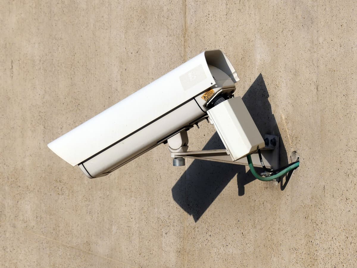White security camera mounted on a sunlit exterior wall